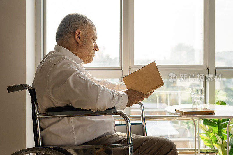 一个成熟的人坐在残疾人的椅子上看书
