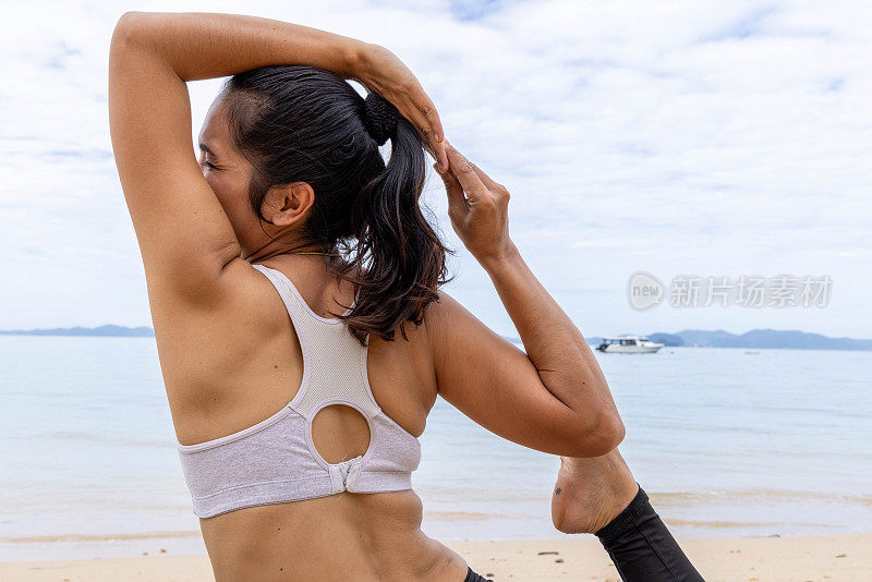 一名泰国妇女在阴天的海边练习瑜伽，找到了宁静