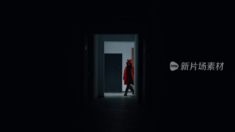 穿红衣服的女人走进一座居民楼的走廊