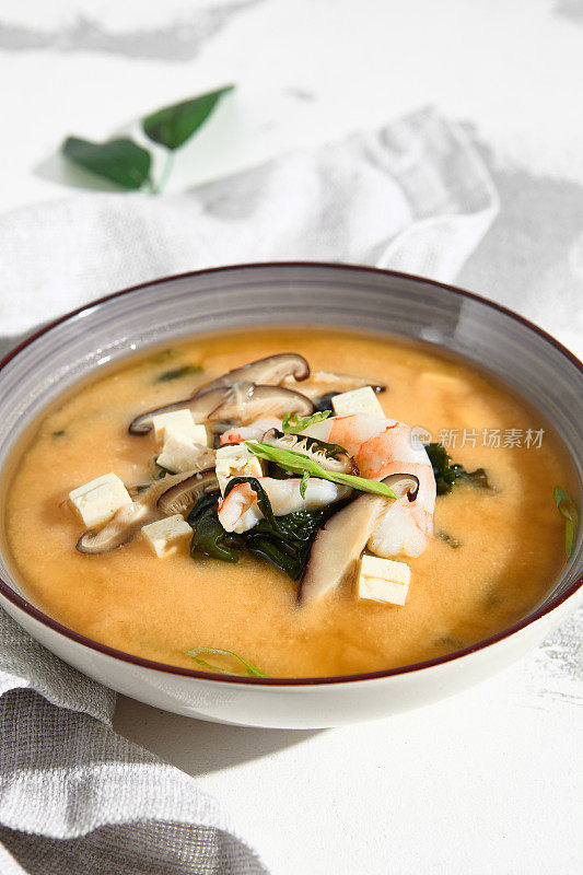 传统的味噌汤，虾，豆腐，蘑菇，用大葱装饰在一个石器碗里