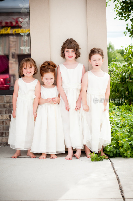 四个穿着白色礼服的花童站在外面