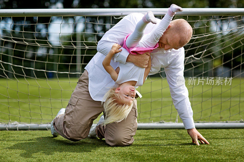 父亲和女儿在足球场踢球