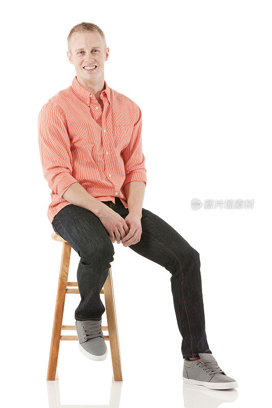 微笑的年轻人坐在凳子上