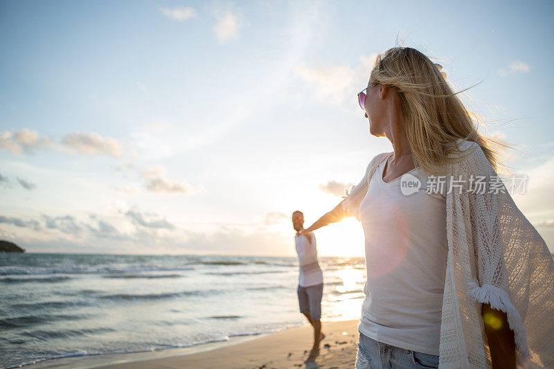 日落时分，一对年轻夫妇在海滩上散步