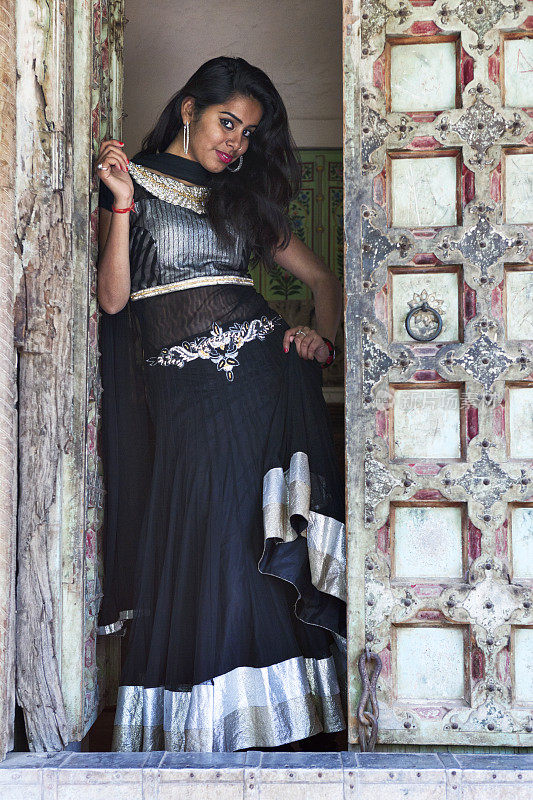 年轻的印度妇女穿着传统服装站在门口