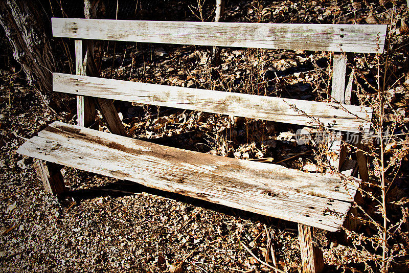 阳光下质朴的老旧风化木凳。全帧图像