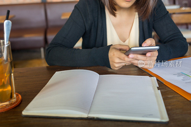 女孩一边做作业一边用智能手机发短信