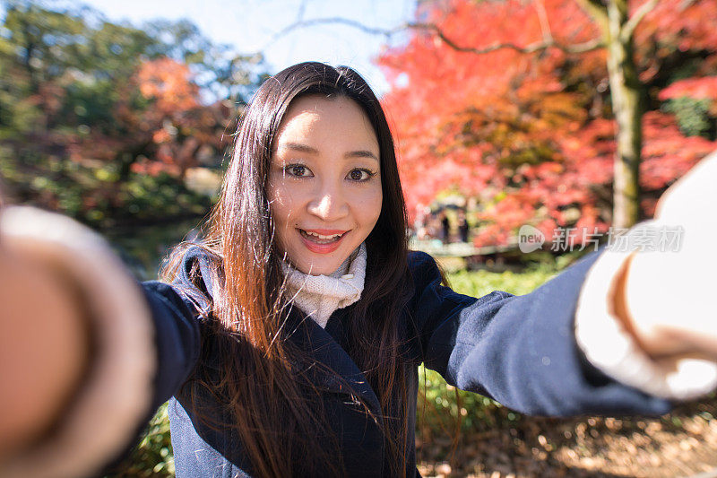 一个女人在秋天的公园里自拍