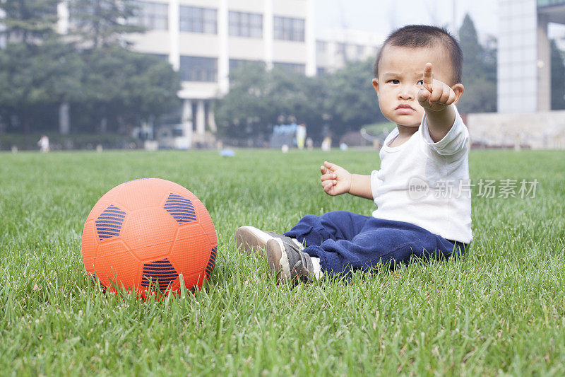 中国男婴在草地上拿着足球