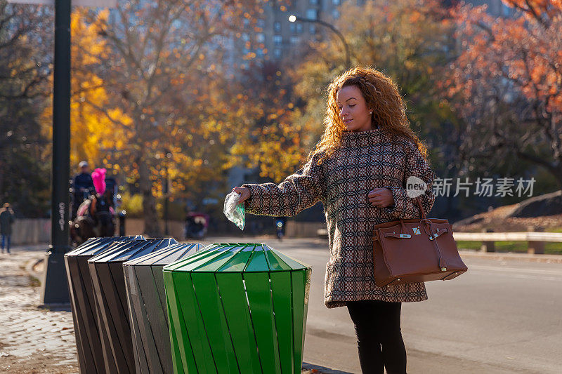 女人在街上把垃圾扔进垃圾桶