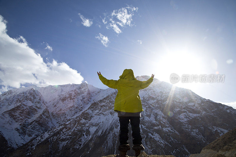 在白雪覆盖的喜马拉雅山脉前伸出双臂的女人