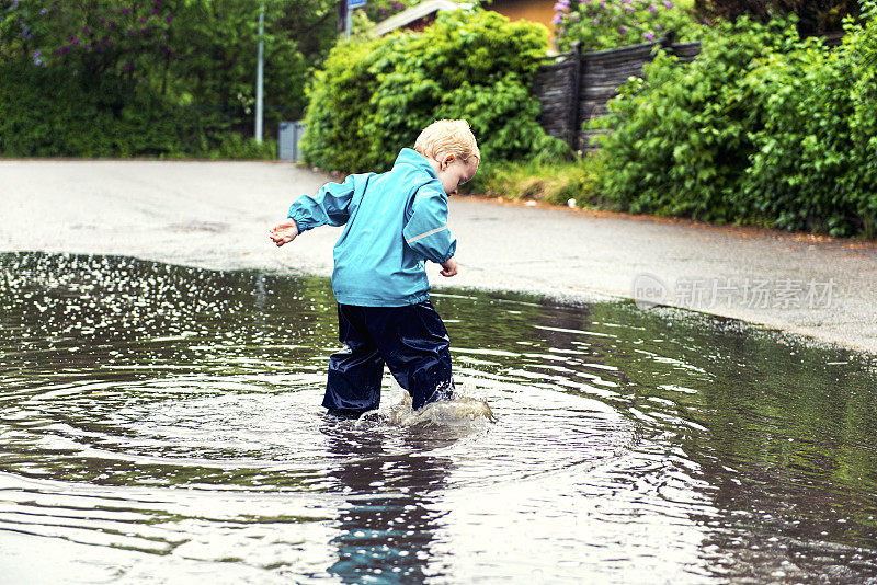 男孩在大雨后走过一个大水坑