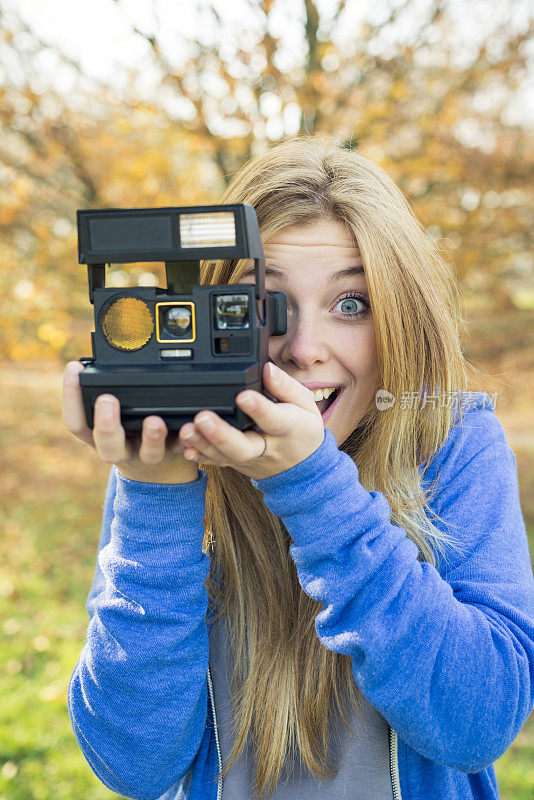 公园里快乐的年轻女子，带着瞬间照相机