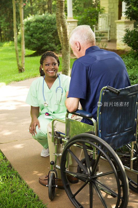 医疗:愉快的护理探望坐在轮椅上的老人。