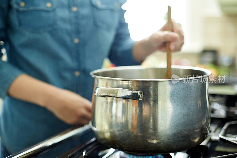 女人用木勺在锅里搅拌食物