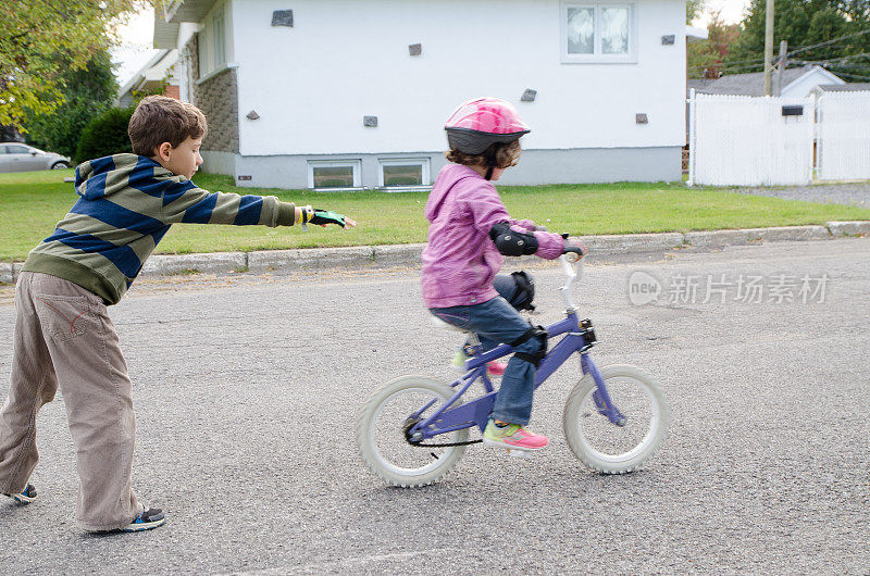 小男孩帮他妹妹骑自行车