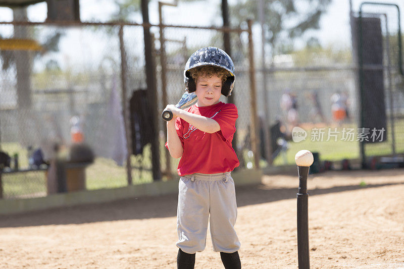 在一场T-Ball棒球比赛中，4岁的男孩准备打棒球