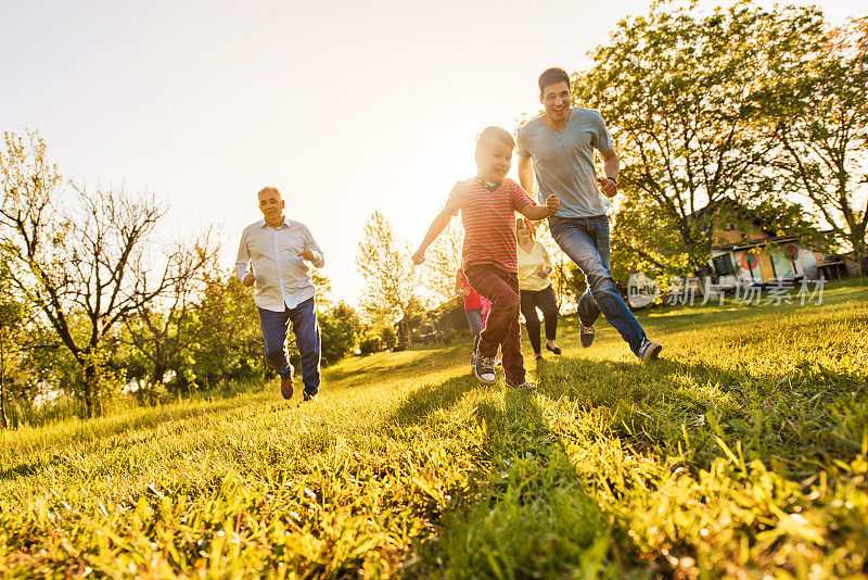 快乐的小男孩和他的家人在草地上跑步。