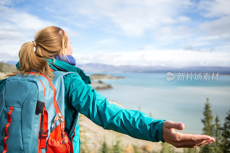 欢呼的女性徒步旅行者伸出手臂俯瞰湖面