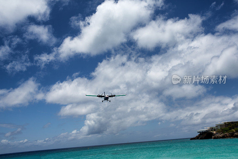 一架小型商用飞机在海滩上空着陆