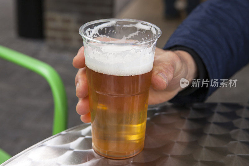 手拿塑料杯里的啤酒