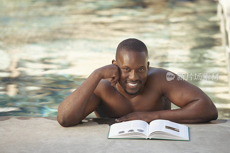 一个男人一边看书一边泡在室外游泳池里