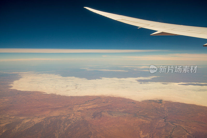透过飞机窗户看到的云朵和天空。飞越澳大利亚内陆沙漠中心上空，澳大利亚北部领土州。