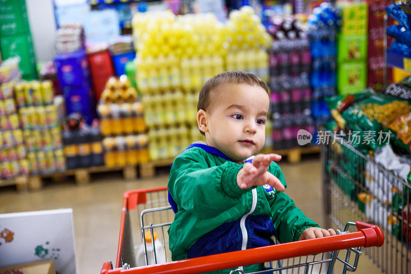 一个小男孩坐在超市的购物车里
