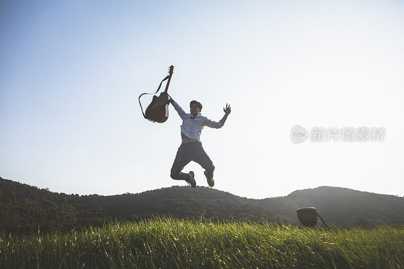 年轻有权势的男人拿着吉他在球场上跳来跳去