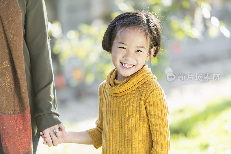 一个亚洲小女孩牵着妈妈的手