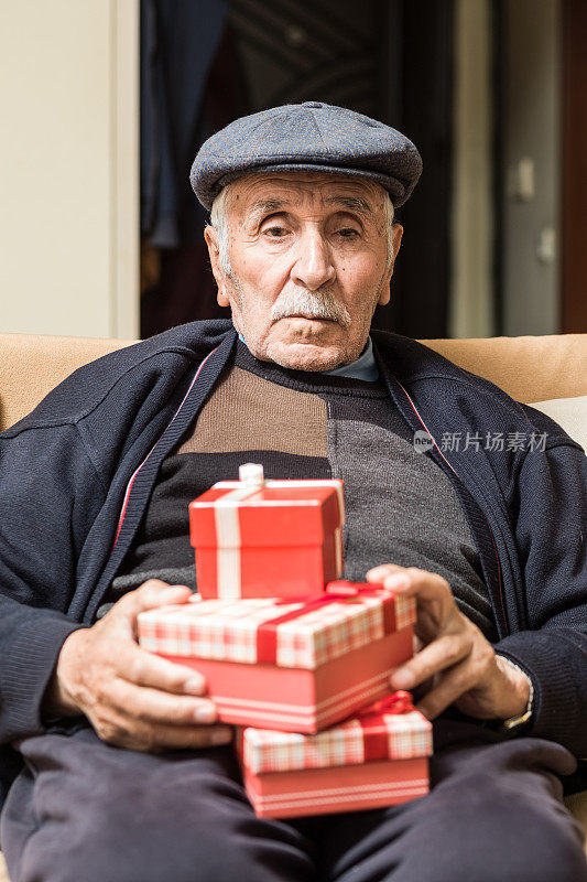 坐在沙发上拿着礼品盒的老人