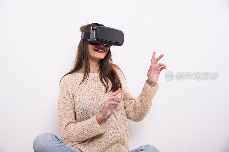 女人戴着虚拟现实头盔坐着，伸出手臂