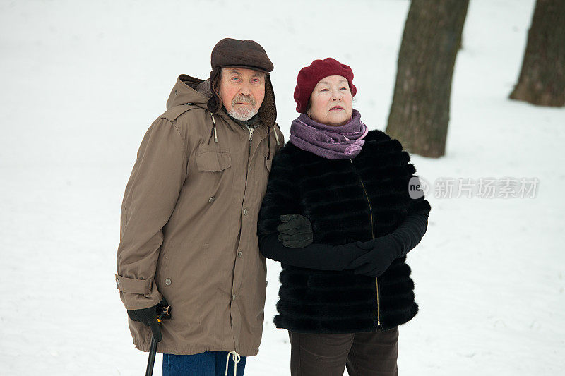老年男女在冬季公园散步