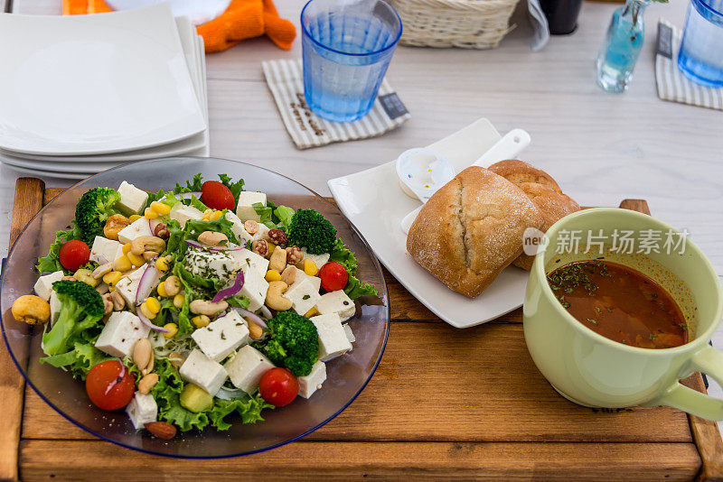 在日本冲绳的一家健康食品咖啡馆或餐厅里，沙拉、汤、面包和饮料以及木桌上的空盘子