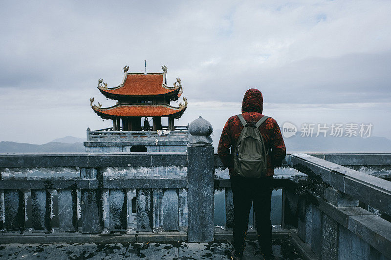 一个背着背包的人在越南看佛教寺庙和雾蒙蒙的山脉