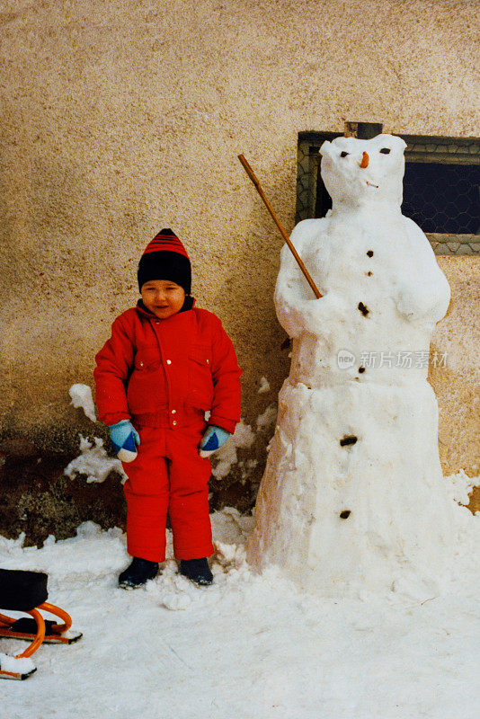 80多岁的小男孩站在雪人旁边