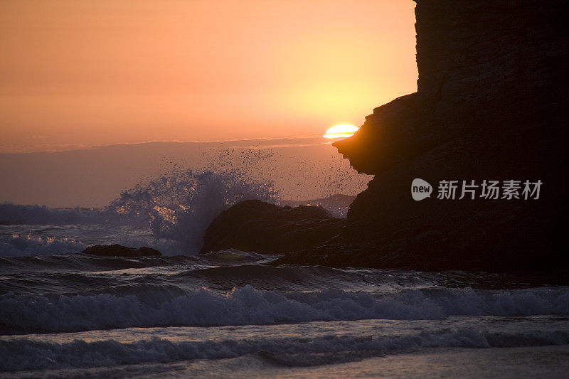 夕阳西下，海浪拍打着岩石的剪影