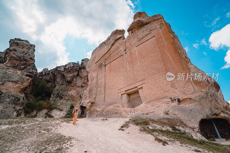 在土耳其弗里吉安河谷的迈达斯古城遗址中，一位美丽的女游客正在观赏迈达斯纪念碑