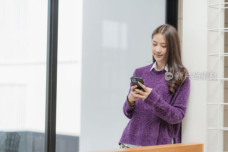 美丽的亚洲女子使用智能手机浏览社交媒体，上网，与朋友聊天，玩网络游戏。网上购物加载在互联网上的应用程序