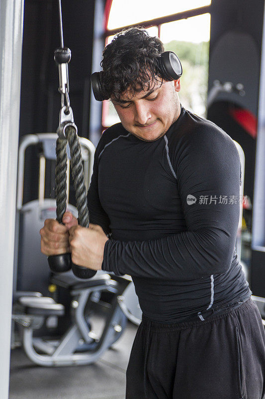 年轻男性健美运动员在健身房训练他的背部肌肉