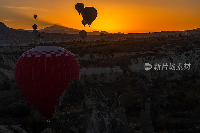 卡帕多西亚爱谷的热气球。阳光慢慢照亮了埃尔西耶斯山。