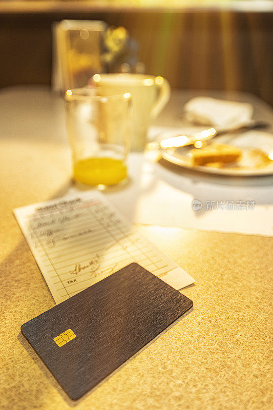 在餐厅用信用卡支付清晨日出的早餐，包括橙汁、烤面包和咖啡。