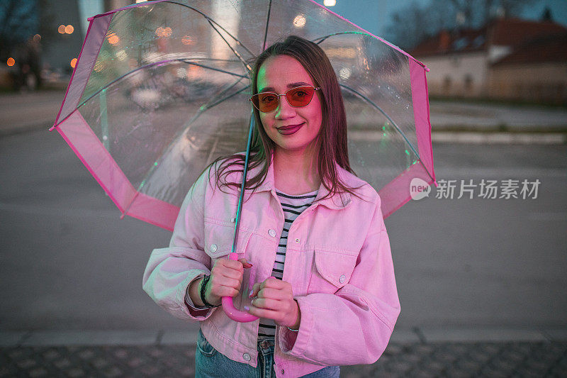 一个美丽的女人在雨夜撑伞散步的肖像