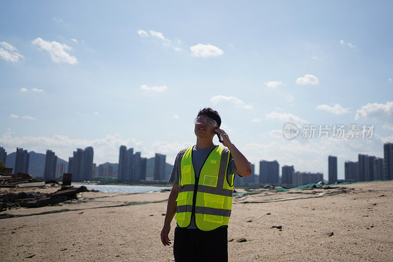 环卫工人在海滩上使用智能设备