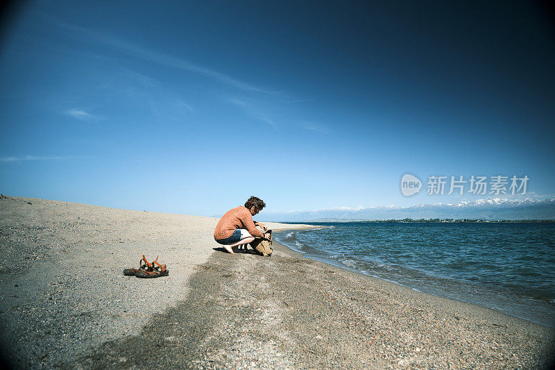 无忧无虑的女游客在大盐湖海滩上从背包里拿樱桃