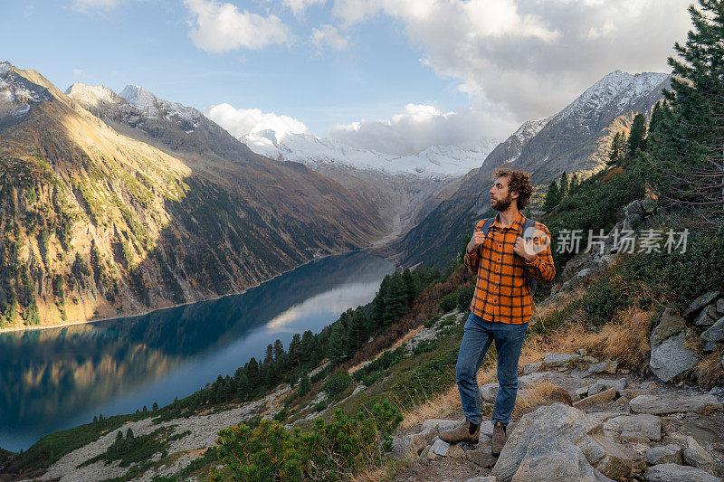 一名男子在湖泊和山脉环绕的欧洲阿尔卑斯山徒步旅行