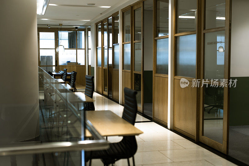 开放式计划共享办公桌和办公椅在一排走廊库存照片