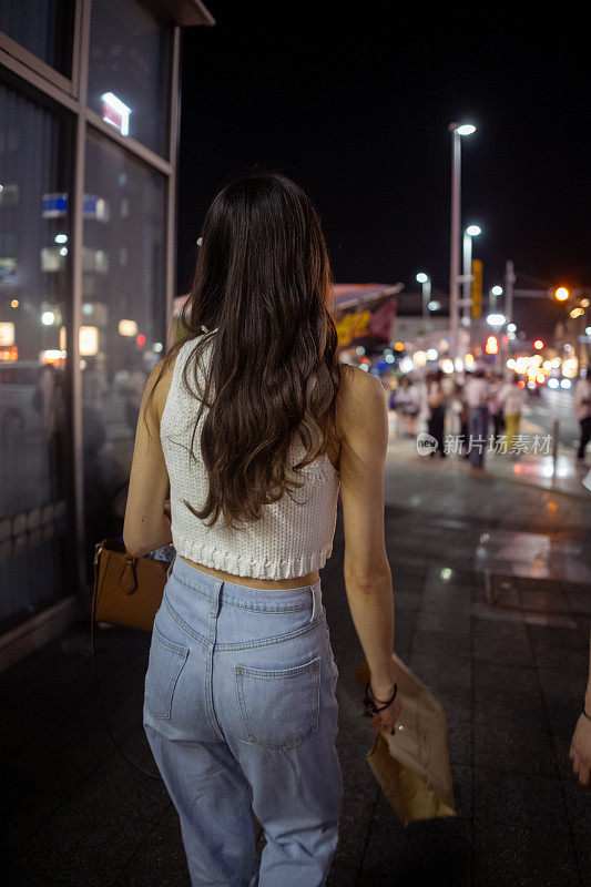 年轻女子走在夜晚的城市