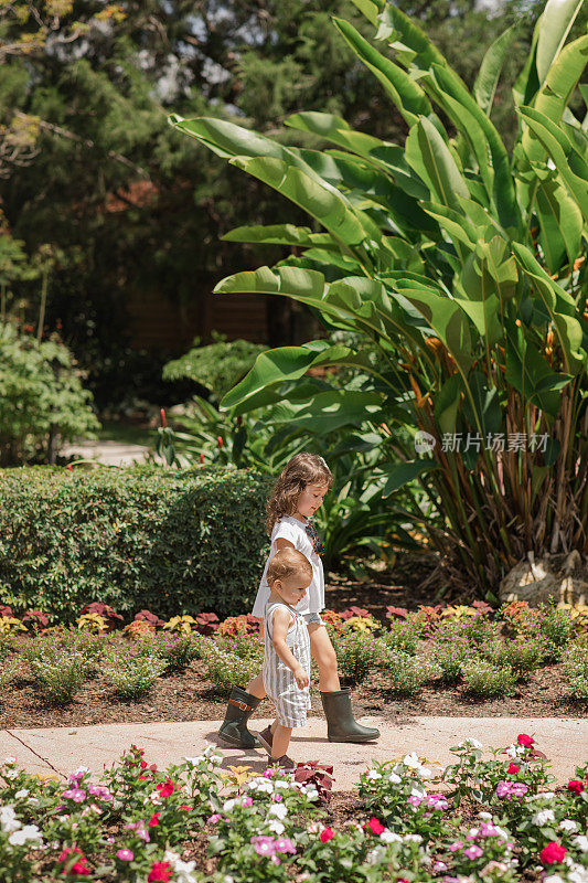生活方式一对年轻的兄弟姐妹在佛罗里达州花园的西棕榈滩牵手散步，穿着鼠尾草绿和白色休闲夏装，古巴裔美国人4岁的蹒跚学步的女孩和1岁的男婴都是棕色头发