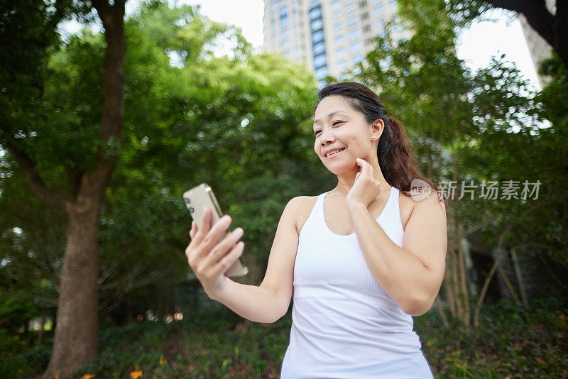 中年女性健身者在户外用手机测量心跳